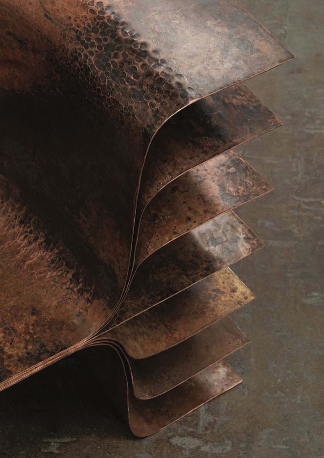 Layered hammered metal sheets with warm patinated surfaces